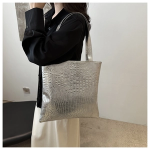 Silver crocodile pattern tote bag shown as a shoulder bag on a model in a minimalist room