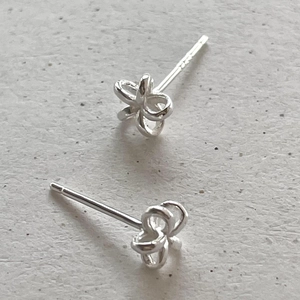 Close-up of minimalist S925 sterling silver flower stud earrings with a polished finish