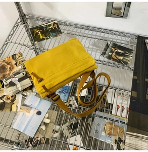Detail view of bright yellow waterproof nylon messenger bag on industrial wire mesh background