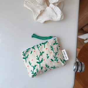 Close-up of floral cotton pouch with green cord zipper and simple wish label detail