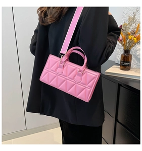 Detailed view of pink geometric textured handbag with wide strap worn with black blazer