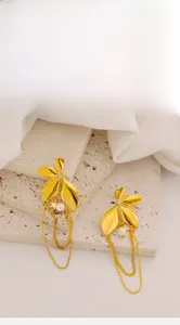 Detail of gold floral tassel earrings with leaf texture, white pearls, and stars on stone