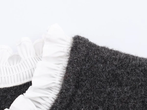 Detail of dark grey knit fabric with white pleated poplin trim on the neckline