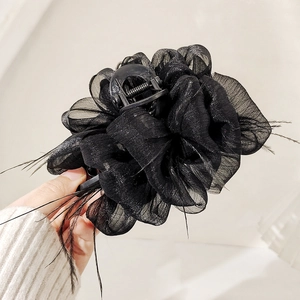 Macro detail of black glittery tulle flower hair claw with elegant ostrich feather accents