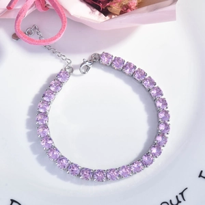 Macro detail of lavender crystal tennis bracelet with silver clasp on white ceramic tray