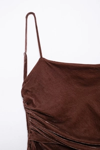 Dettaglio dell'abito in velluto marrone con spalline sottili e texture plissettata