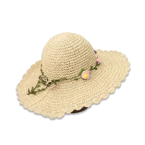 Detailaufnahme vom Strohhut mit gewelltem Rand und dekorativem Blumenkranz für Damen