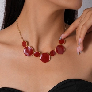 Gros plan d'un mannequin portant un collier géométrique rouge avec chaîne dorée chic