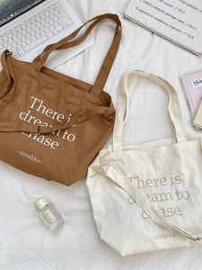 Minimalist canvas tote bags in brown and white with letter print on fabric background