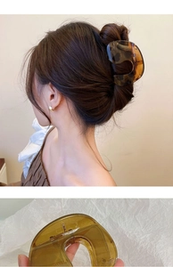 Detail view of large amber resin hair claw clip with model showcase and close-up texture