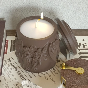 Dettaglio di candela marrone accesa con rilievo di angelo su uno sfondo stile vintage