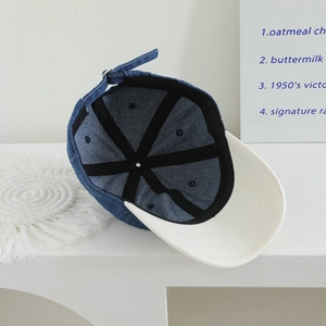 Internal view of a blue denim baseball cap with white brim and metal adjustment strap