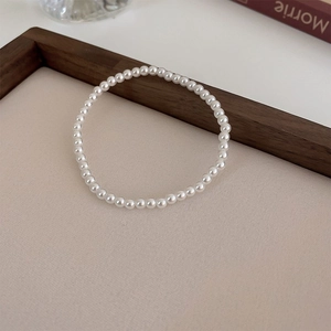 Close-up of elegant minimalist pearl elastic bracelet on a neutral beige background