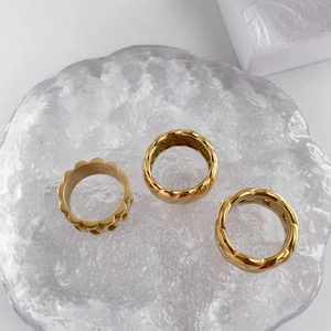 Nahaufnahme von drei goldfarbenen Ringen mit Kettengliedern auf Glasteller