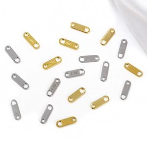 Macro view of gold and silver stainless steel oval charms with S.STEEL and K18 engravings