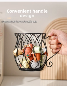 Handheld view of a coffee cup shaped black metal wire basket for capsule storage
