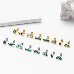 Set of gold and silver stud earrings with green zircon stones on professional stone props