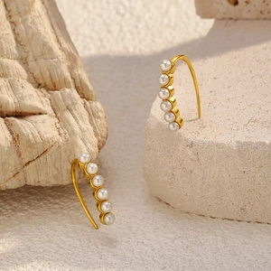 Elegant gold titanium steel earrings with white pearls on a natural stone base
