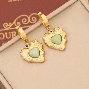 Detailed shot of vintage heart earrings with green stones and gold textured metal finish