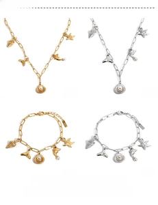 Detail view of gold and silver ocean charms with shells and starfish on paperclip chains