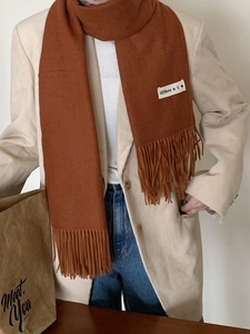 Close-up of caramel orange cashmere scarf with tassel details and fabric label