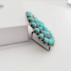 Macro view of vintage Y2K belt buckle with turquoise stones and floral metal patterns