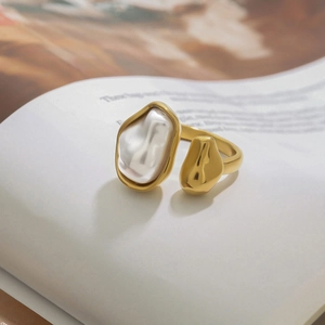 Close-up of golden baroque pearl ring on open book with elegant vintage aesthetic