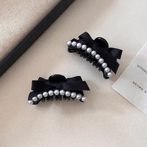 Detailed shot of French style black bow hair clip with elegant white pearl trim