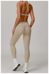 Detail of cross-back beige sports bra and high-waisted yoga leggings with seamless texture