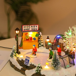 Detailed view of glowing LED Christmas village hockey shop with resin skaters and snow decor