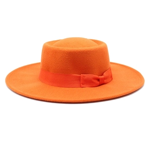 Close-up of bright orange wool felt pork pie hat featuring tonal grosgrain ribbon detail