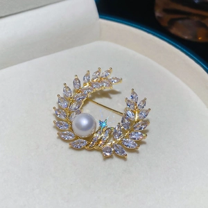 Detailed close-up of 18k gold-plated pearl brooch with zircon wheat ear wreath design