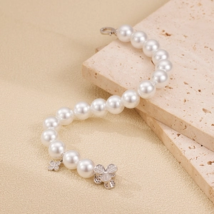 925 silver pearl bracelet with sparkling zircon clover charms on beige marble surface