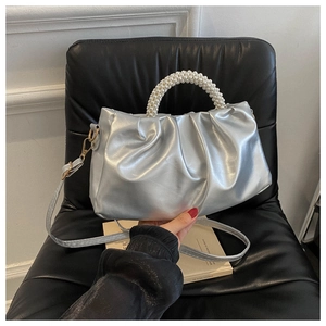 Detail of silver pleated bag featuring pearl handle and glossy metallic leather texture