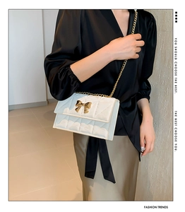 Detailansicht der weißen Stepptasche mit goldener Schleife und Kette am Model getragen