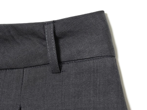 Close-up detail of dark grey wool pants showing belt loops and twill fabric texture
