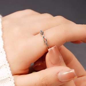 Gros plan d'une bague chaîne en argent sur le doigt avec un fond en maille délicate
