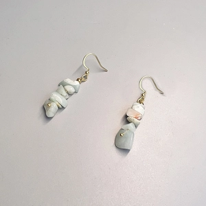 Detail of handmade bohemian earrings with natural light green and white crystal stones
