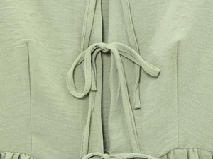 Detailed close-up of the light green tie-up knot and breathable linen texture fabric