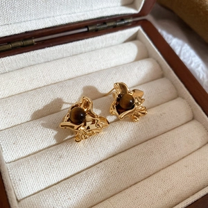 Macro detail of vintage tiger eye stone earrings with pleated gold metal base texture