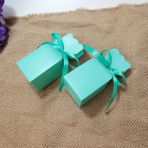 Close-up of teal gift boxes with silk ribbons on rustic burlap for holiday favors