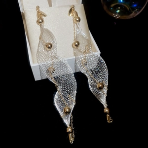Macro shot of elegant mesh pearl tassel earrings hanging on a white jewelry box edge