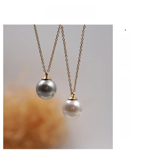 Dettaglio di eleganti perle tonde grigie e bianche su catenine girocollo placcate oro 18k