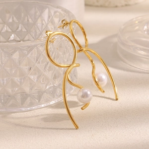 Detail of 18K gold plated knotted metal earrings featuring elegant hanging faux pearls