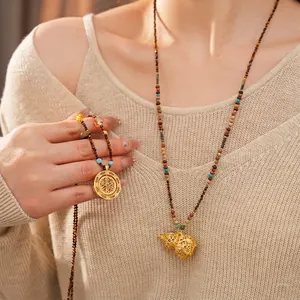 Tiger eye beaded necklace with hollow filigree gourd pendant on beige knitwear