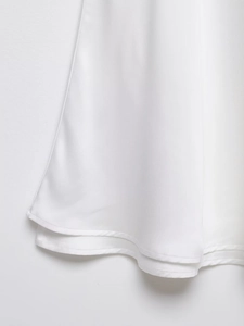 Gros plan sur l'ourlet piqué et le tissu blanc lisse d'une robe avec dentelle en V