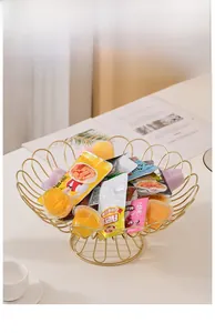 Detailed view of a wavy gold wire fruit basket filled with snacks on a minimal desk