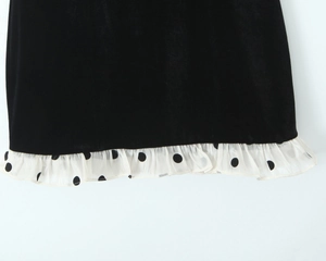 Détail de l'ourlet en velours noir avec bordure à volants en mousseline à pois blancs