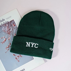 Close-up of dark green ribbed knit beanie with white NYC 19 3D embroidery detail