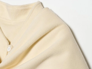 Macro view of cream wool blend fabric texture with a round white button detail